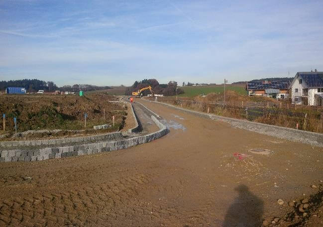 Bauarbeiten im neuen Wohngebiet Moosen-West, mit Baustellenfahrzeugen und ungenutztem Grundstück in Halsbach, Bayern.